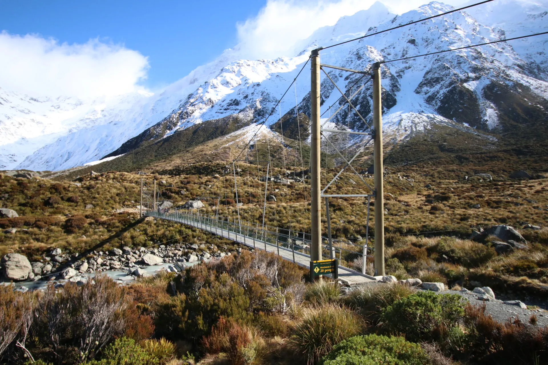 胡克谷步道上的吊橋橫越河谷,後方是積雪的山峰